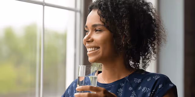 a person holding a lass f water and smiling