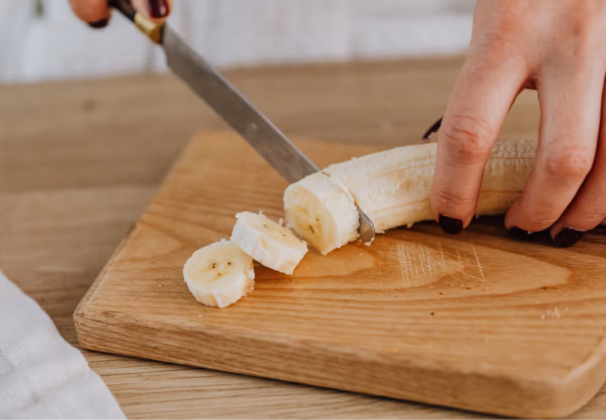 a banana being sliced on a cutting board