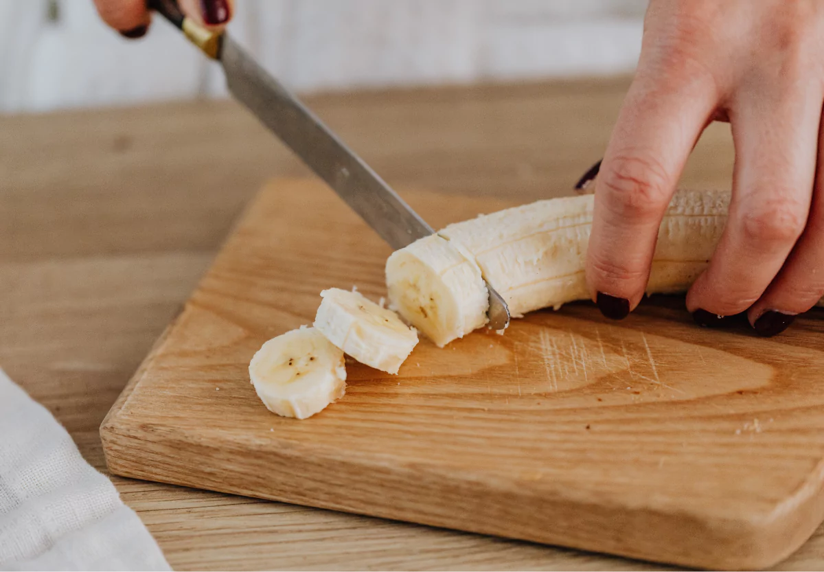 a banana being sliced on a cutting board