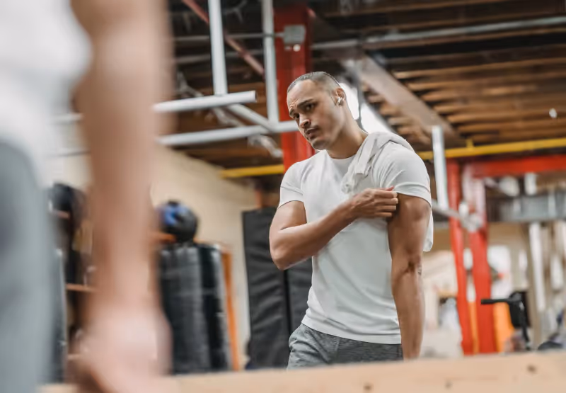 a man looking at his biceps in the gym