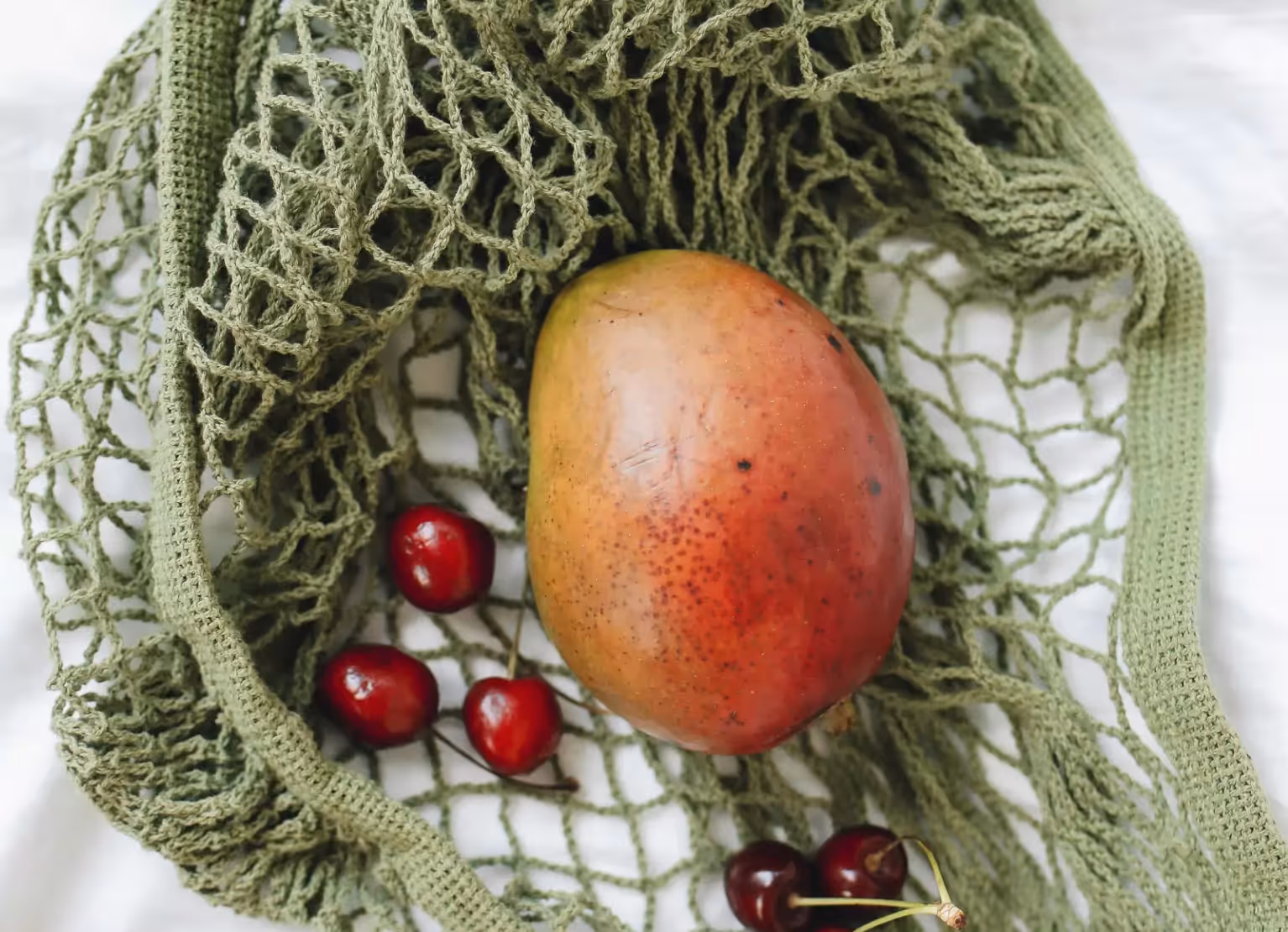 Mesh bag with mango and cherries