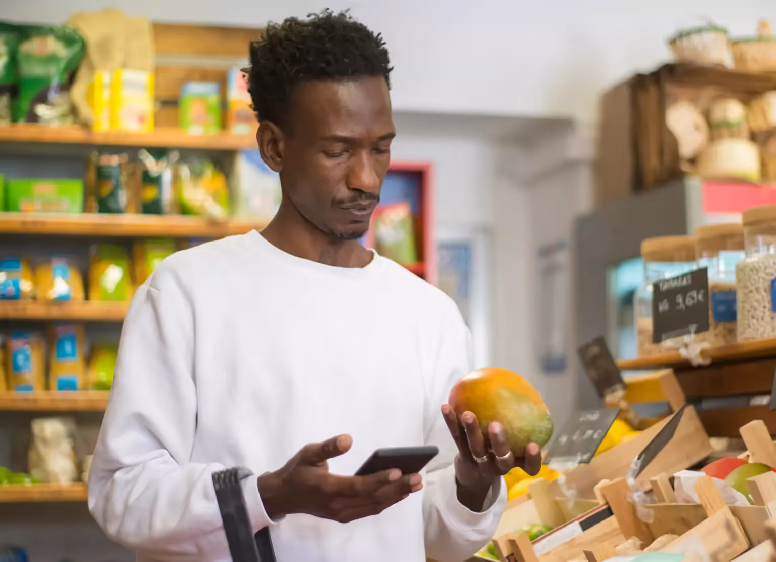 Person checking mango at grocery store