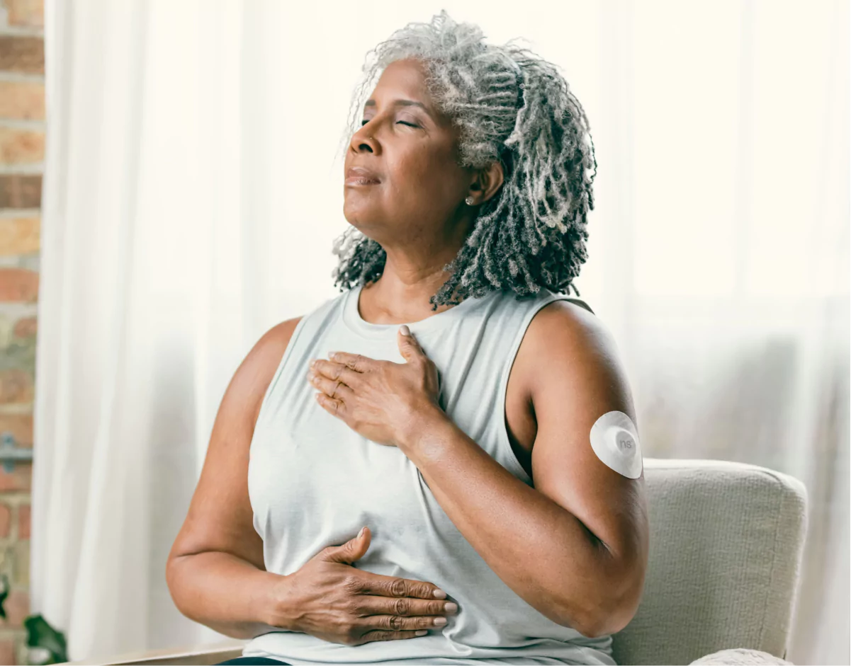 a woman taking a deep breath with a CGM on