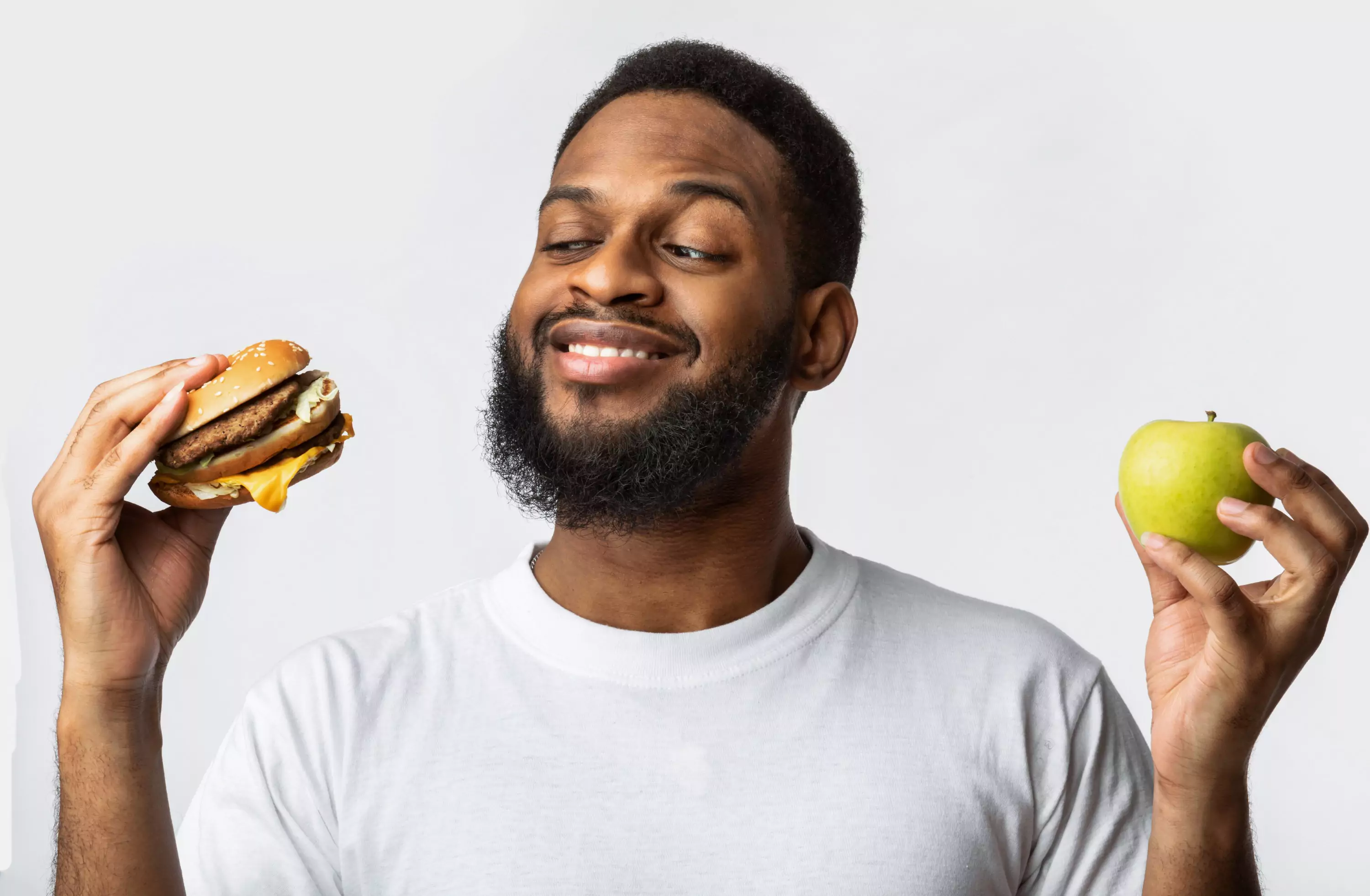 a person holding a burger on one hand and an apple on another 