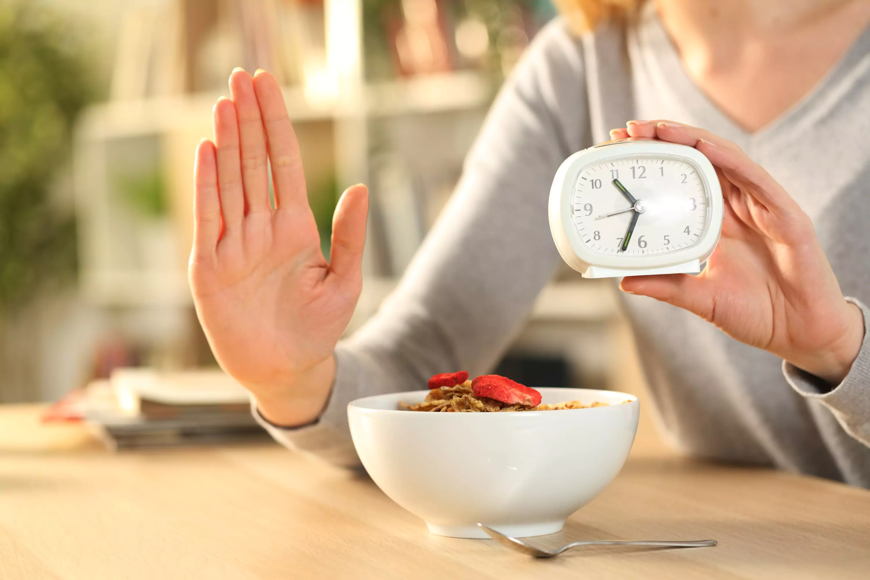 a person showing a stop sign with one hand and holding a clock with another
