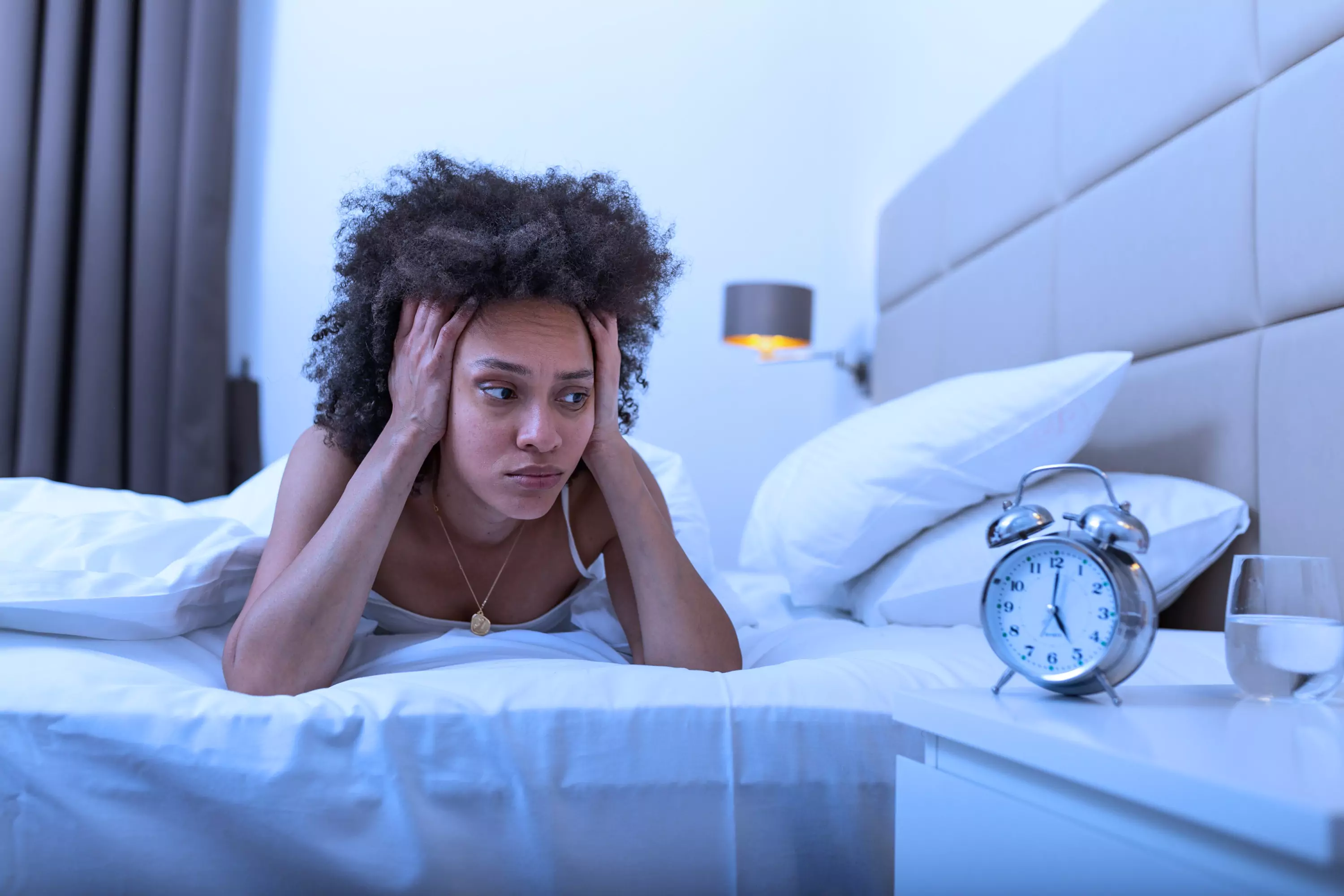 a person laying in bed looking at a clock