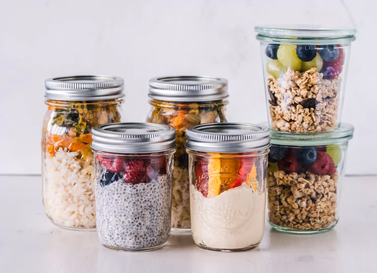 Jars of chia pudding, veggies, fruits, sauerkraut, and granola