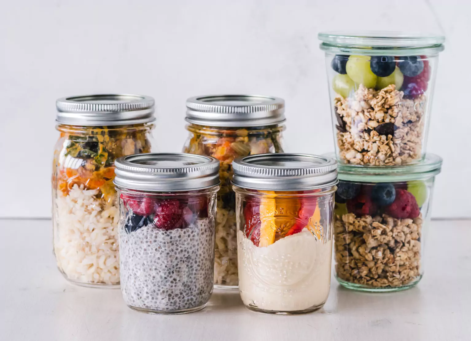 Jars of chia pudding, veggies, fruits, sauerkraut, and granola