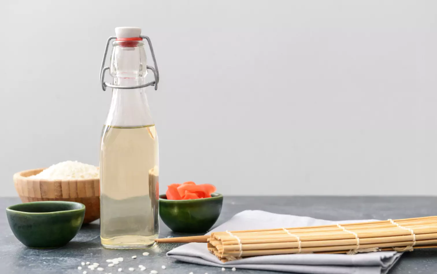 a bottle of vinegar, a bowl of rice and a pair of chopsticks