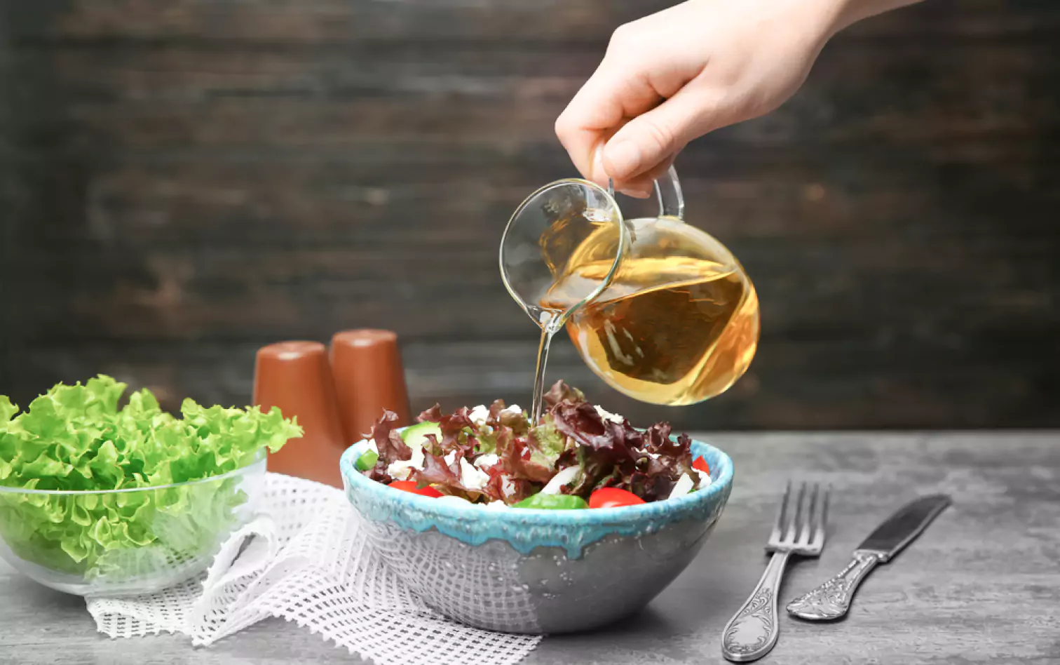 a person pouring the vinegar over a salad