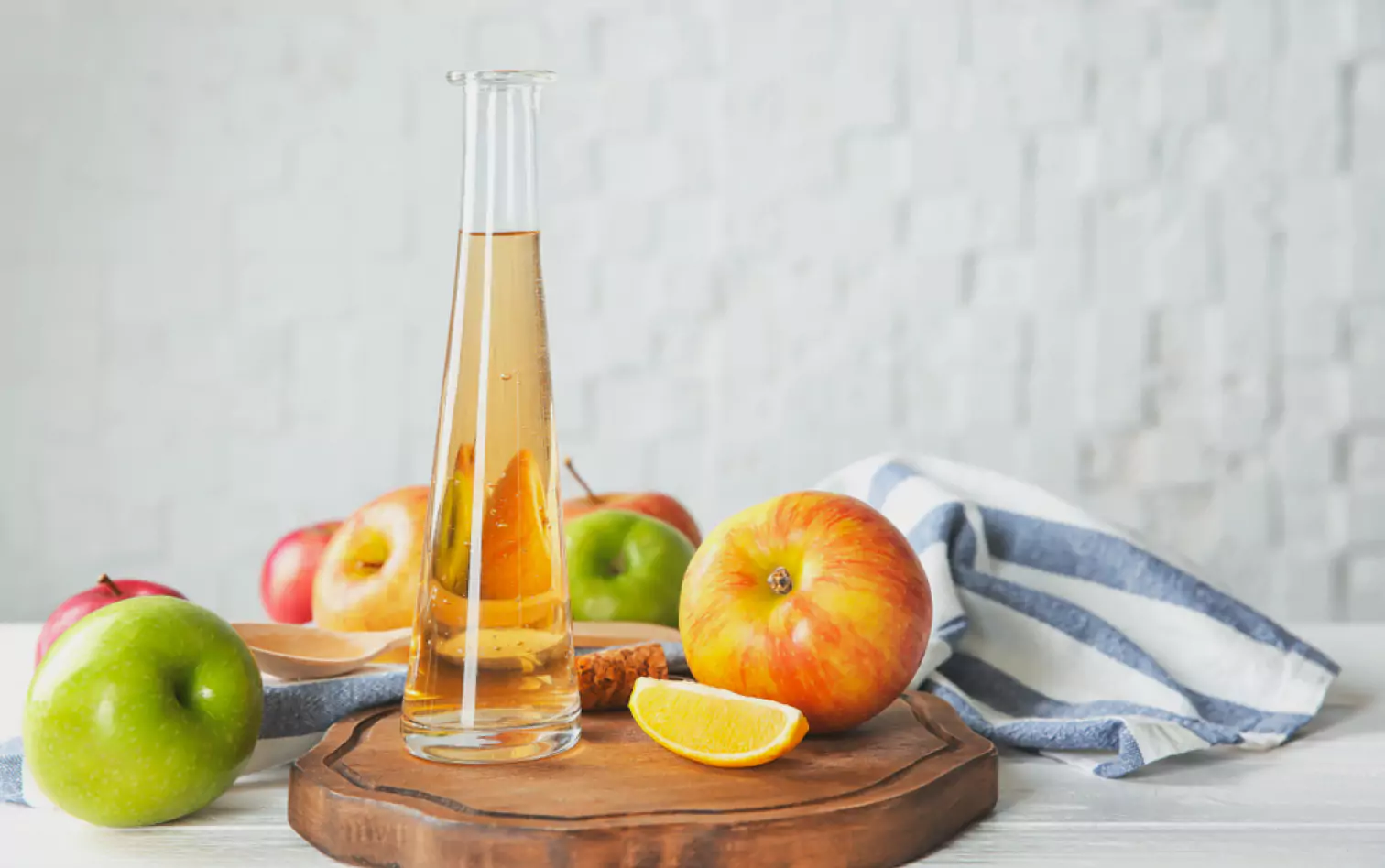 a bottle of vinegar and apples on a board