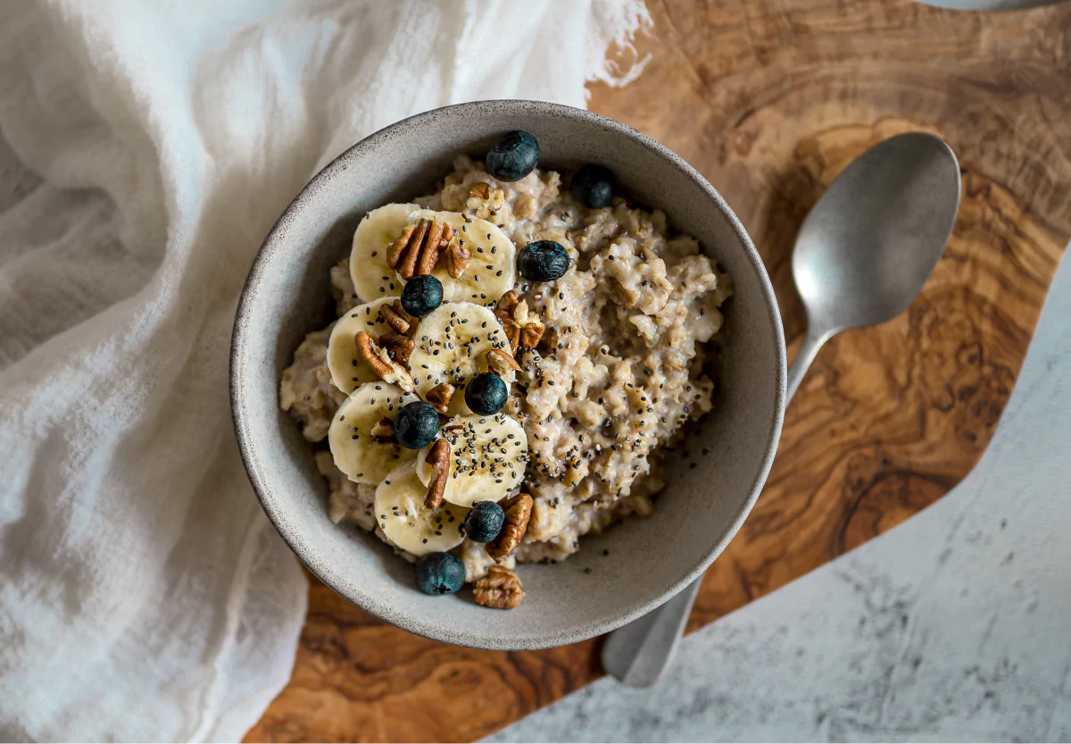 a bowl of oatmeal with bananas, nuts and berries