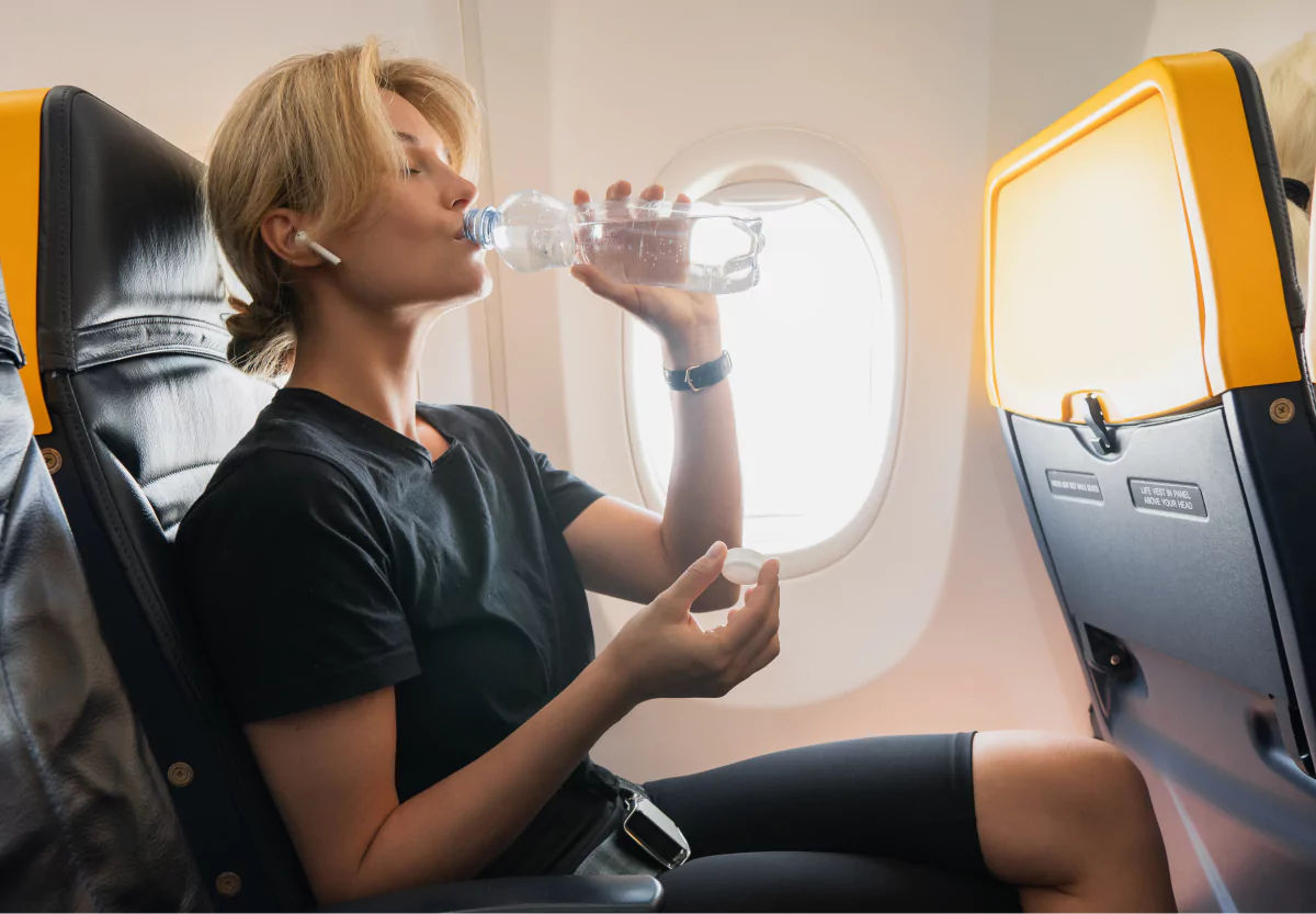 a girl drinking from a water bottle on a plane