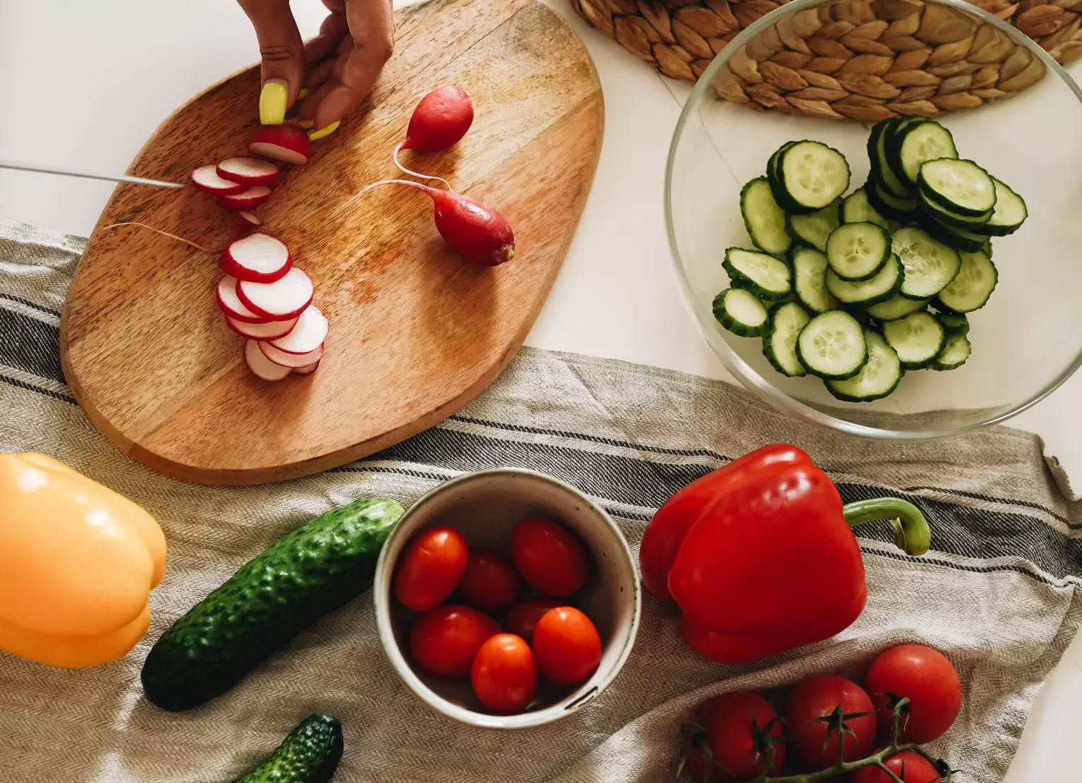 someone slicing radishes and cucumbers