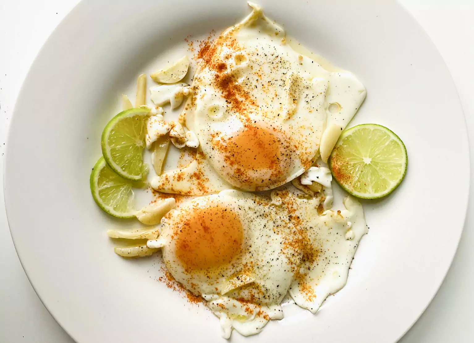a plate of fried eggs, garlic and lime