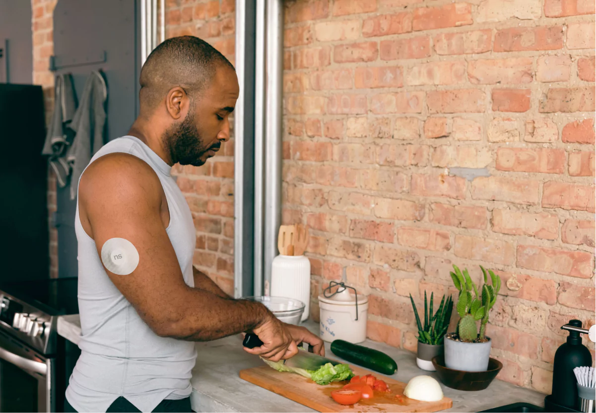 a man with a nutrisense cgm patch cooking