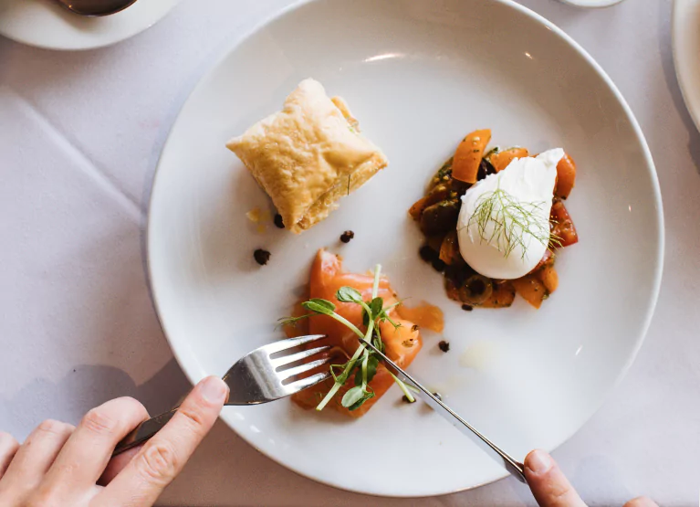 someone cutting into a small bite of food on a plate