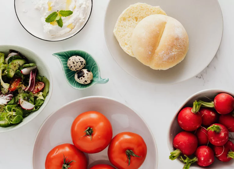 a few plates with tomatoes, bread, cheese, and a salad