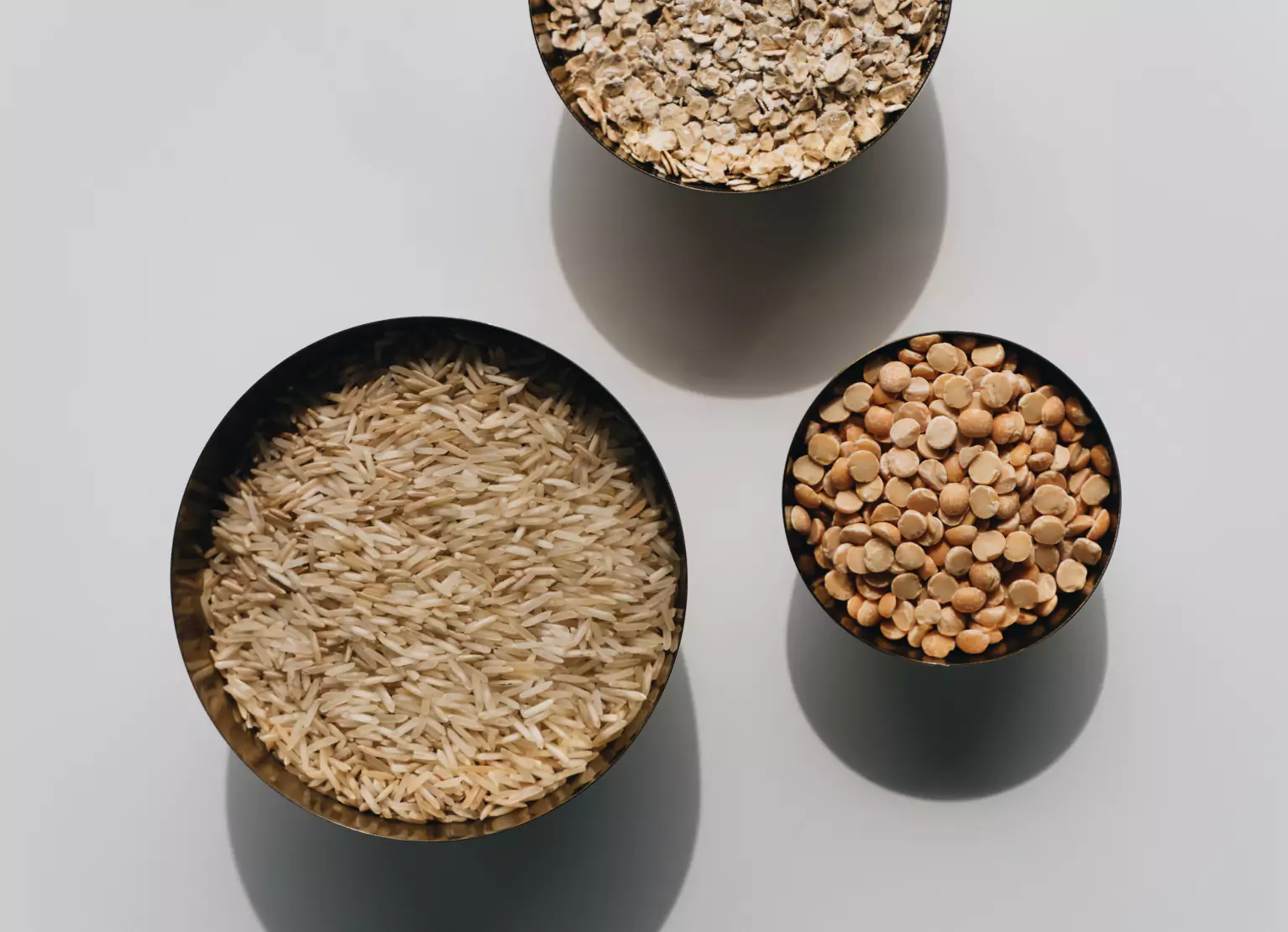 a bowl of rice, a bowl f peas and a bowl of rolled oats