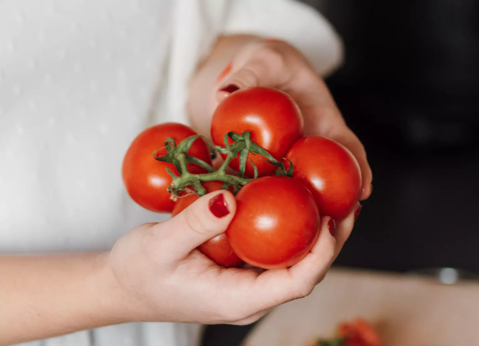 someone holding 5 tomatoes